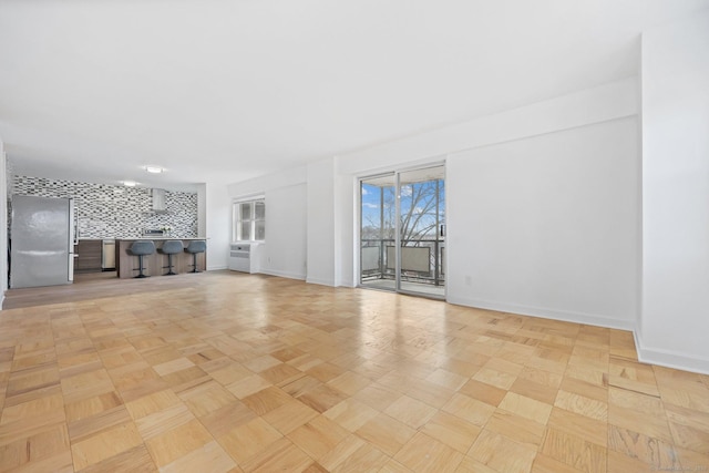 unfurnished living room with baseboards