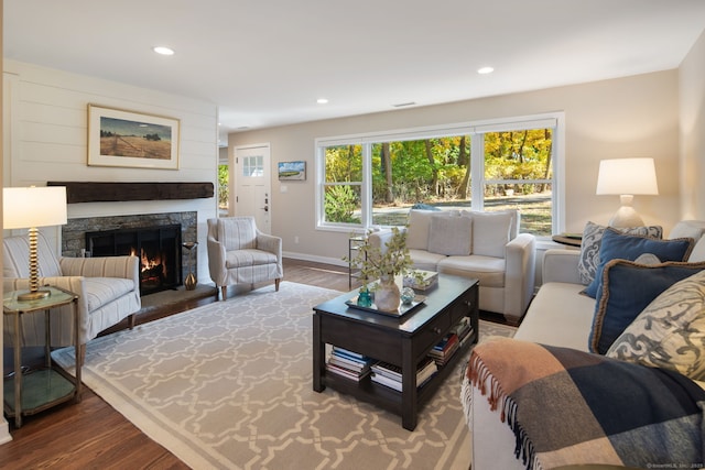 living area with baseboards, a lit fireplace, wood finished floors, and recessed lighting