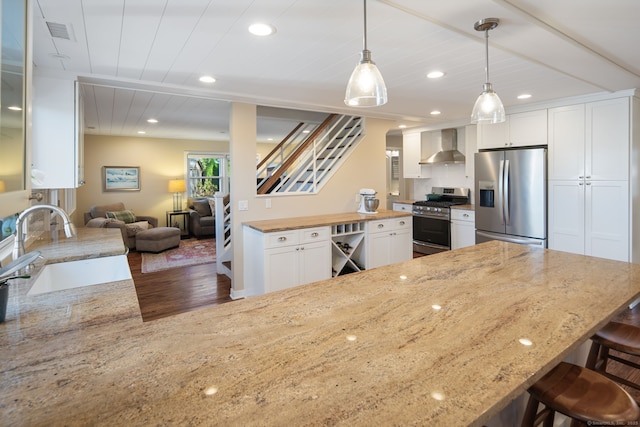 kitchen featuring appliances with stainless steel finishes, visible vents, wall chimney range hood, and white cabinetry