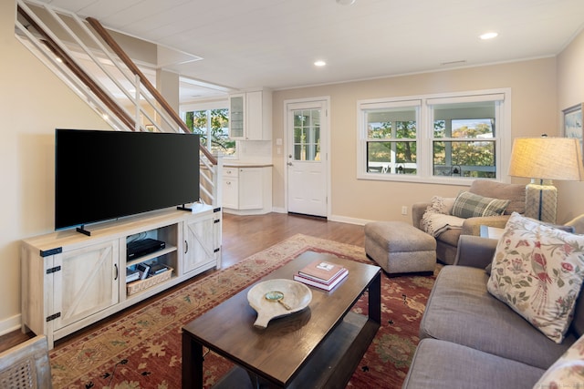 living area with baseboards, wood finished floors, and recessed lighting