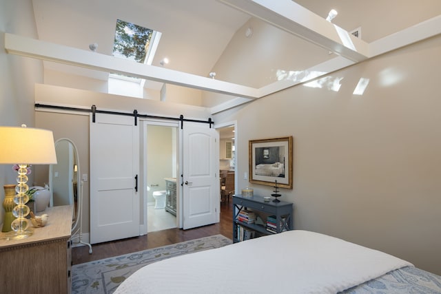 bedroom featuring ensuite bathroom, high vaulted ceiling, a barn door, a skylight, and wood finished floors