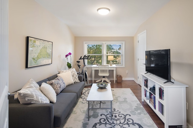 living room with lofted ceiling, dark wood-type flooring, and baseboards