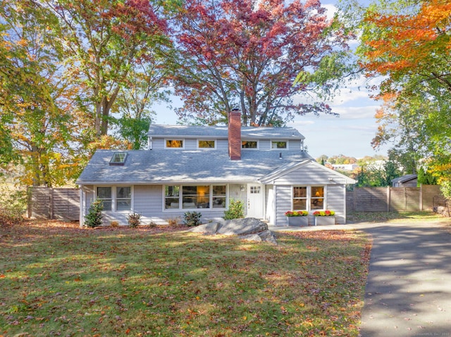 view of front of house featuring a chimney, fence, and a front yard