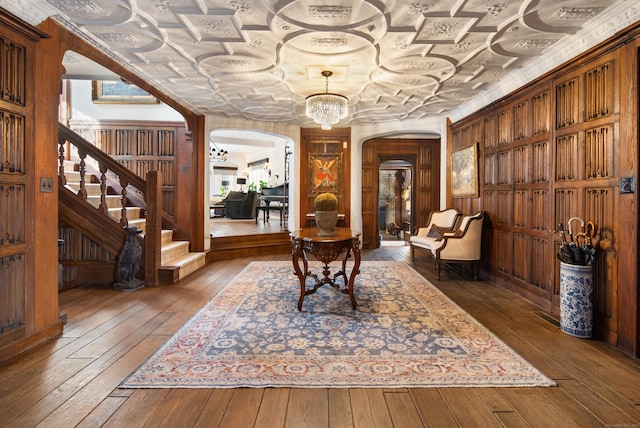 living area featuring arched walkways, hardwood / wood-style floors, stairs, and an ornate ceiling