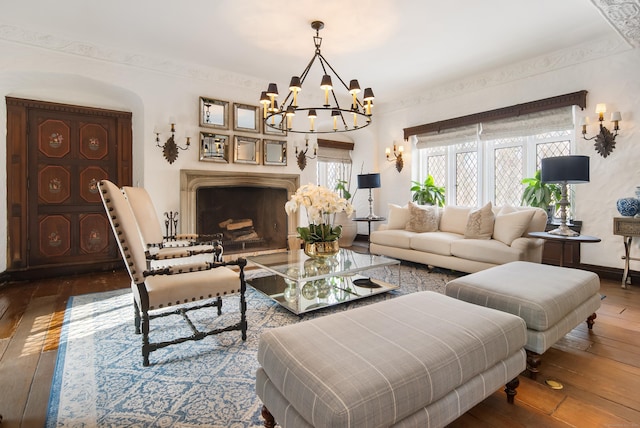 living area featuring wood-type flooring, a fireplace, baseboards, and a notable chandelier