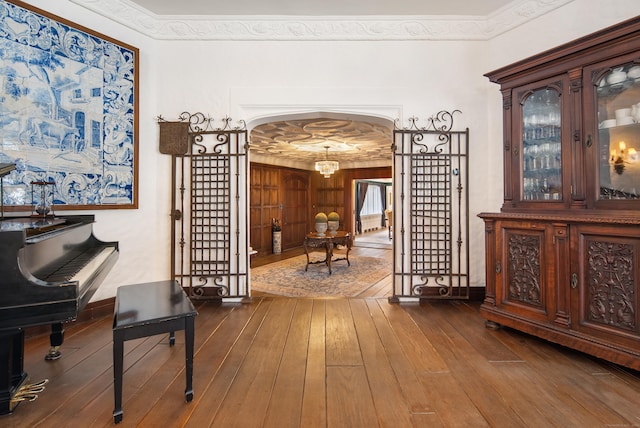 hallway featuring ornamental molding, arched walkways, dark wood finished floors, and baseboards