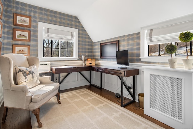 office space featuring lofted ceiling, radiator, wainscoting, wood finished floors, and wallpapered walls