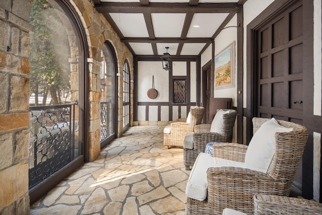 sitting room with coffered ceiling, beam ceiling, and stone floors