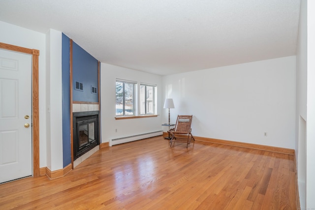 sitting room featuring a baseboard radiator, visible vents, a tiled fireplace, light wood-style floors, and baseboards