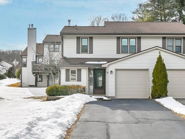 view of front facade featuring driveway, an attached garage, and a chimney