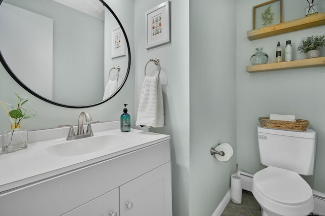 half bathroom with baseboards, vanity, and toilet