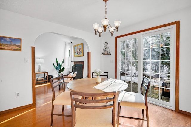 dining area featuring light wood-style flooring, arched walkways, and baseboards