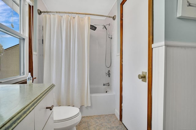 bathroom featuring wainscoting, shower / bath combo, and toilet