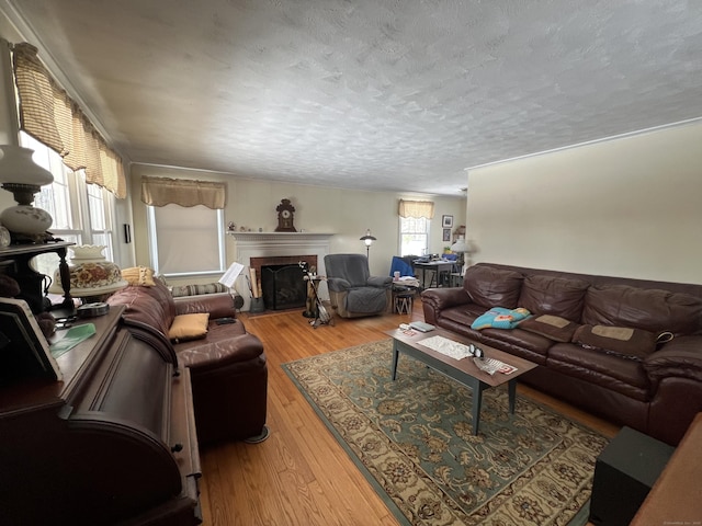 living room featuring a fireplace with flush hearth, a textured ceiling, and wood finished floors