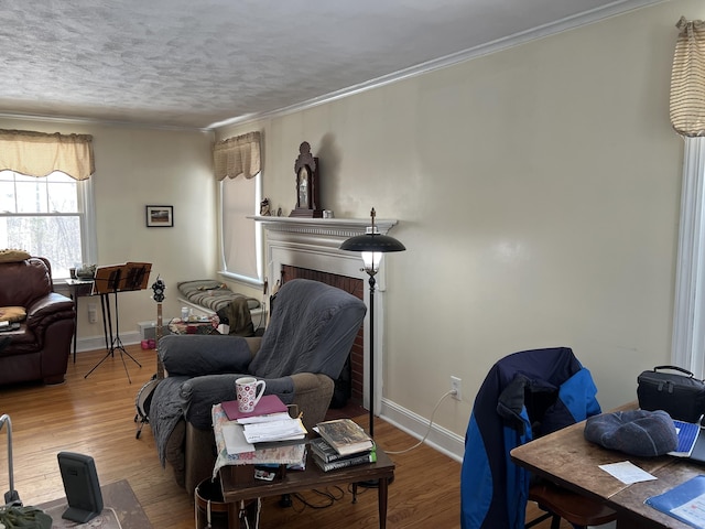 living area featuring baseboards, a fireplace, ornamental molding, and wood finished floors