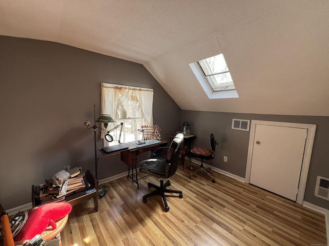 office with lofted ceiling, visible vents, and wood finished floors