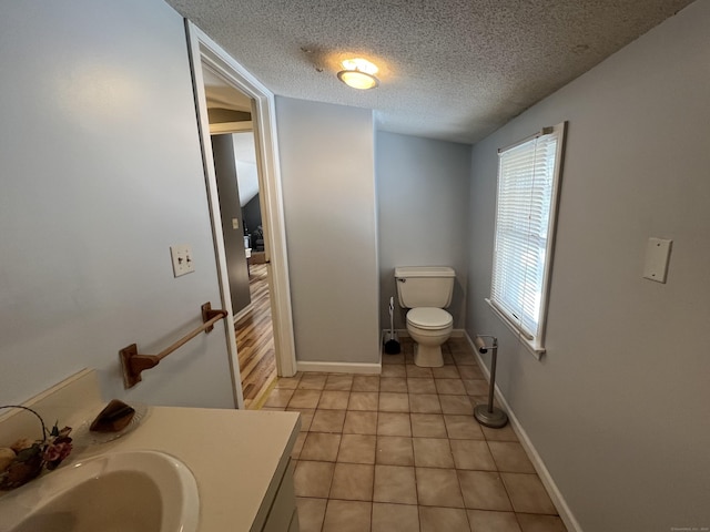 bathroom featuring baseboards, toilet, tile patterned floors, a textured ceiling, and vanity