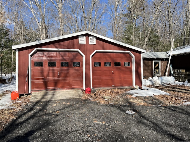 snow covered garage featuring aphalt driveway