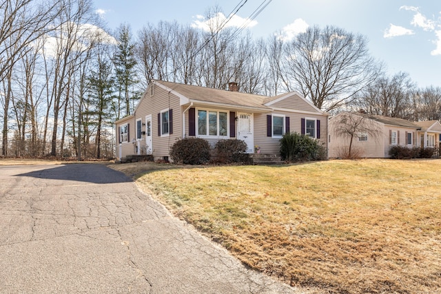 single story home featuring aphalt driveway, a chimney, and a front yard