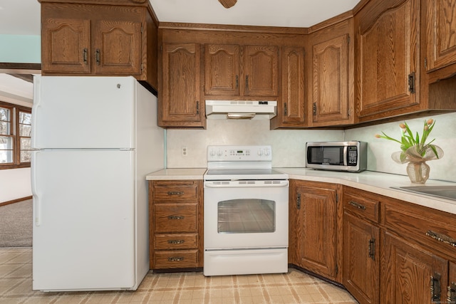 kitchen featuring white appliances, light countertops, brown cabinets, and under cabinet range hood