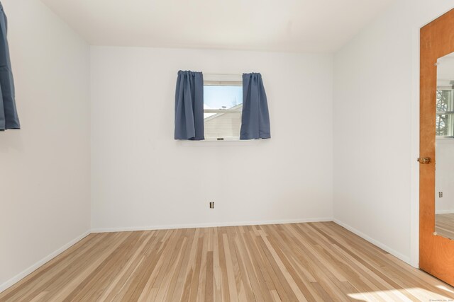 unfurnished room featuring wood finished floors, baseboards, and a wealth of natural light