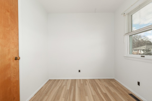 empty room featuring light wood-type flooring, baseboards, and visible vents