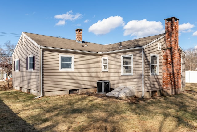 back of property with central air condition unit, a chimney, and a yard