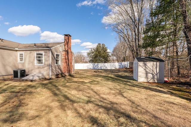 view of yard featuring an outbuilding, fence, central AC unit, and a shed