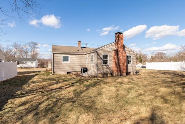 rear view of property featuring fence, a lawn, and a chimney