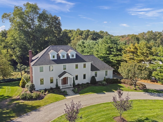 view of front of home with a front lawn and a view of trees