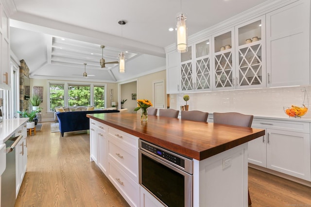 kitchen with stainless steel appliances, butcher block counters, light wood-type flooring, and decorative backsplash