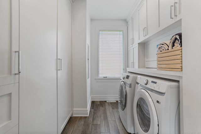 clothes washing area featuring cabinet space, washing machine and dryer, dark wood finished floors, and a wealth of natural light