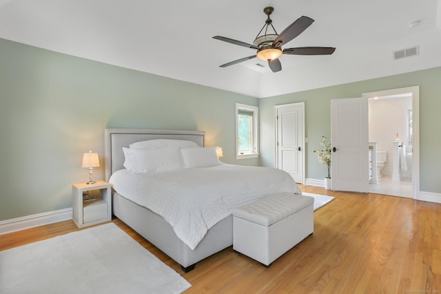 bedroom with vaulted ceiling, light wood finished floors, visible vents, and baseboards