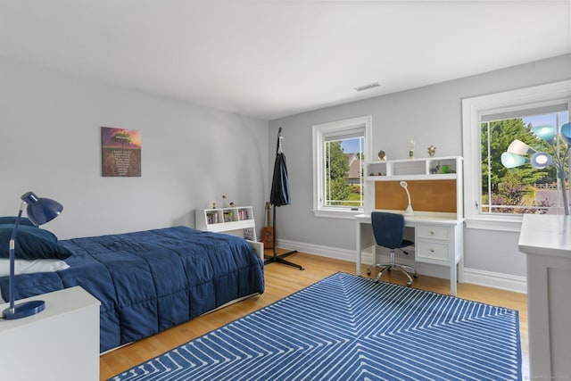 bedroom with light wood finished floors, visible vents, and baseboards