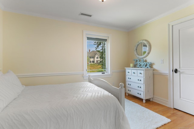 bedroom with baseboards, visible vents, wood finished floors, and ornamental molding