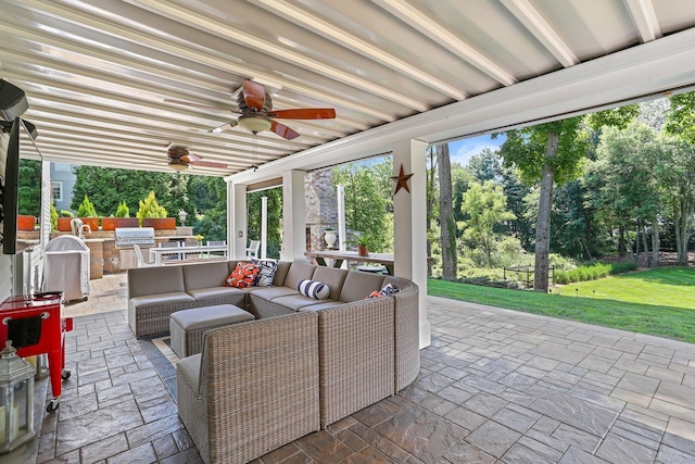 view of patio with area for grilling, ceiling fan, an outdoor living space, and an outdoor kitchen