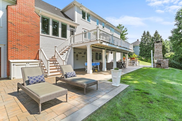 rear view of house featuring a lawn, stairway, a wooden deck, a patio area, and an outdoor living space with a fireplace