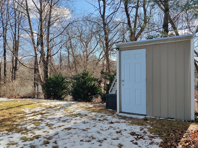 snow covered structure featuring a storage shed and an outdoor structure