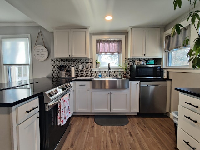 kitchen with a peninsula, dark countertops, stainless steel appliances, and a sink