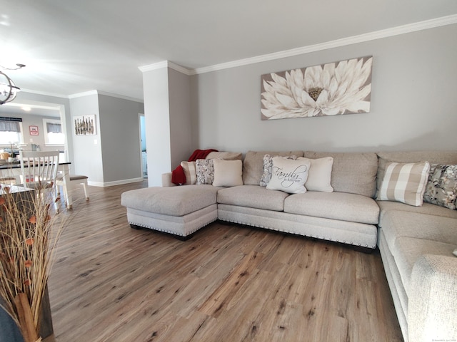 living room featuring an inviting chandelier, crown molding, baseboards, and wood finished floors