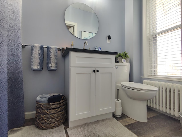 full bath featuring toilet, radiator heating unit, wood finished floors, and vanity