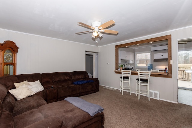 carpeted living area with ornamental molding, visible vents, and ceiling fan