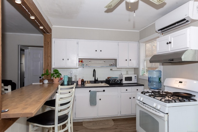 kitchen with under cabinet range hood, white appliances, a sink, white cabinets, and a wall mounted AC