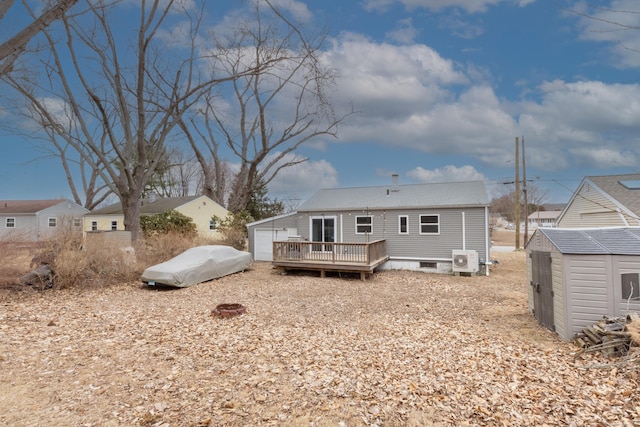 back of house with an outbuilding, a detached garage, a wooden deck, and a shed