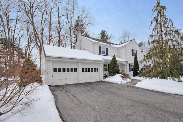 view of front of property with a garage, aphalt driveway, and a chimney