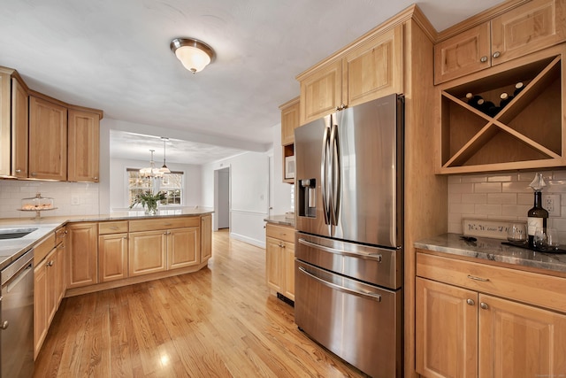 kitchen with decorative backsplash, appliances with stainless steel finishes, a peninsula, light wood-style floors, and light brown cabinets