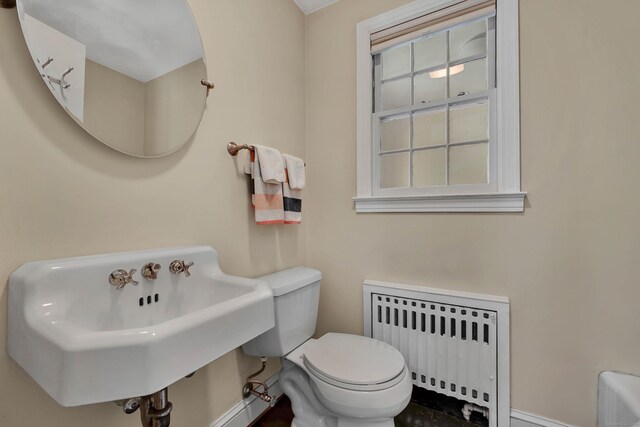 bathroom with toilet, radiator heating unit, and a sink