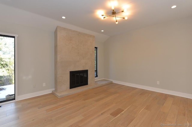 unfurnished living room with recessed lighting, light wood-style floors, vaulted ceiling, a fireplace, and baseboards