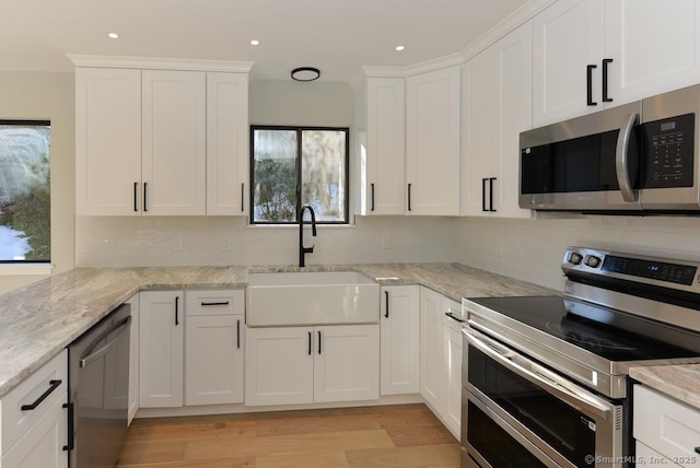 kitchen featuring white cabinetry, stainless steel appliances, decorative backsplash, and a sink