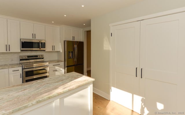 kitchen with light wood finished floors, recessed lighting, white cabinets, and appliances with stainless steel finishes